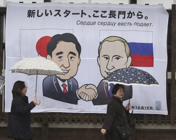 People walk in front of banner of Russian President Vladimir Putin and Japanese Prime Minister Shinzo Abe characters meeting in Nagato, western Japan, Wednesday, Dec. 14, 2016. Russia's President Vladimir Putin will visit Japan on Thursday where he will meet with Japan's Prime Minister Shinzo Abe to negotiate over a 70-year-old island dispute that has kept them from signing a peace treaty. (AP Photo/Koji Sasahara)